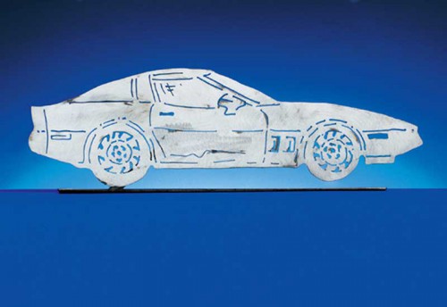 The 1984 - 1991 C4 Corvette Coupe.  Each CarArtWork Corvette sculpture is 17 inches long and is mounted on a flat metal base. The sculpture is securely attached to the base with a single metal rod affixed to the rear of the piece. The mounting rod is positioned so that its appearance is minimized from the front view of the sculpture. Each piece has a brushed metal finish and is coated with clear lacquer to preserve its luster.